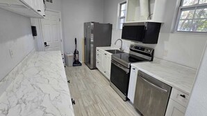 A compact kitchen with white marble countertops, a stainless steel refrigerator, a built-in oven, and a microwave. - Spacious 5-Bd Tampa Retreat with Dual Jacuzzis. Close to Top Attractions. (Tampa)
