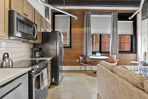 Una cocina compacta con electrodomésticos modernos, un comedor con mesa y sillas, y un sofá.