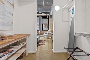 Un pasillo estrecho con una mesa de madera y libros, una silla y una lámpara colgante.
