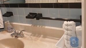 Ett badrum med handfat, handduksställ och en korg med toalettartiklar.