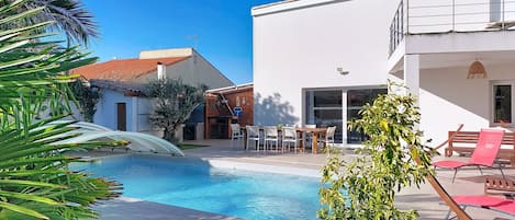 A swimming pool with a waterfall feature, surrounded by a patio area with outdoor furniture.