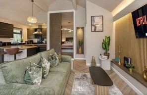 A modern living room with a sofa, a coffee table, and a TV mounted on the wall. - Maple Lodge - sleeps 2 guests in 1 bedroom (South Duffield)