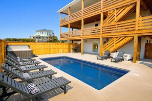 Une piscine avec des chaises longues et une terrasse en bois.