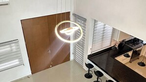 Una cucina moderna con un piano di lavoro nero, quattro sgabelli da bar e una lampada a sospensione.