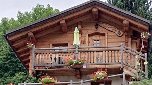 A wooden chalet with a balcony, a small porch area, and a stone staircase leading up to the entrance. - Le Refuge Des Marmottes (BEAUFORT)