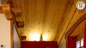 A compact kitchen with wooden ceiling beams, red cabinets, a gas stove, and a microwave. - Le Refuge Des Marmottes (BEAUFORT)