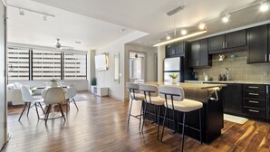Uma cozinha moderna com uma ilha central, banquetas de bar e um espaço de jantar com mesa e cadeiras.