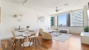Un soggiorno moderno con zona pranzo, un divano bianco, un tavolo rotondo e una ventola a soffitto.