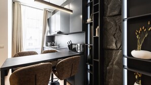 A modern kitchen with a dark countertop, two chairs, a built-in stove, and a stone accent wall. - Posh and stylish apartment with a queen-size bed (Wien)