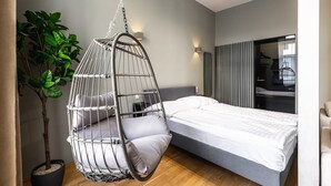 A modern bedroom with a hanging chair, a bed, a potted plant, and a mirror. - Posh and stylish apartment with a queen-size bed (Wien)