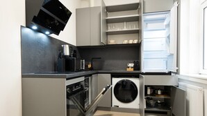 Una cocina compacta con horno integrado, cafetera y microondas.