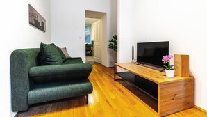 A modern living room with a green sofa, a wooden coffee table, a flat-screen TV, and a potted orchid. - Precious apartment in calm district area (Wien)
