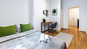 A modern bedroom with a bed, green pillows, a desk with a chair, a potted plant, and a framed picture on the wall. - Precious apartment in calm district area (Wien)