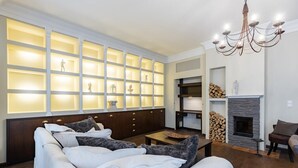 Een moderne woonkamer met een hoekbank, een open haard en een inbouwkast met verlichte panelen.