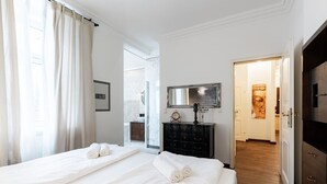 Een hotelkamer met twee bedden, een kaptafel, een spiegel en een badkamer die door een geopende deur zichtbaar is.