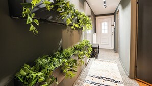 A hallway with a wall-mounted TV, a bench, and a patterned rug. - Cosy, brand new 2-bedroom apartment (Wien)