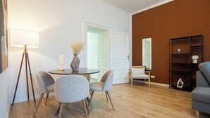 Ein modernes Wohnzimmer mit einem runden Tisch, vier Stühlen, einer Stehlampe, einem Bücherregal und einem Spiegel.