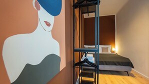 Ein Schlafzimmer mit einem Bett, Holzboden, einem Wandregal und einem großen abstrakten Gemälde.