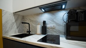 Une cuisine équipée d’un robinet noir, d’un porte-essuie-tout, d’un four à micro-ondes et d’une prise de courant.