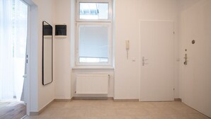 Un couloir avec un radiateur, une porte et une fenêtre équipée de stores.