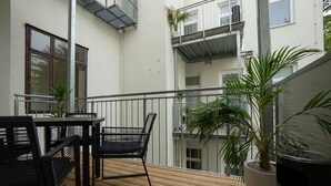 A wooden deck with a table and chairs, surrounded by potted plants. - Bright, modern and central flat with a terrace (Wien)