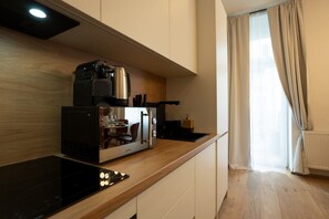 A compact kitchen with a built-in stove, a coffee machine, and a small dining area. - Bright, modern and central flat with a terrace (Wien)