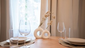 Een eettafel gedekt met borden, glazen en een vaas met gedroogde planten.