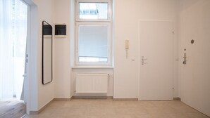 Een gang met een radiator, een deur en een raam met jaloezieën.