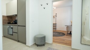 A modern kitchen with a built-in oven and a grey ottoman. There is a dining area with a round rug and a chair. - Modern apartment with a balcony near Belvedere (Wien)