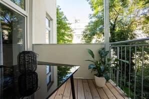 A balcony with a wooden floor, a potted plant, and a glass table with woven baskets. - Modern apartment with a balcony near Belvedere (Wien)