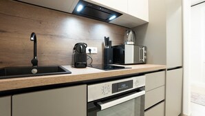 A modern kitchen with a wooden countertop, a built-in oven, a coffee maker, and a microwave. - Modern apartment with a balcony near Belvedere (Wien)