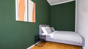 Une chambre à coucher comprenant un lit, une table de chevet et une œuvre d’art accrochée au mur.
