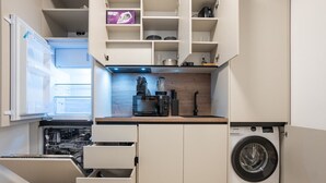 Une cuisine compacte équipée d’un lave-vaisselle, d’une machine à café et d’un lave-linge.