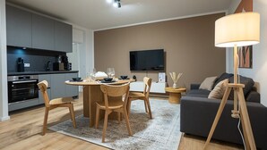 Ein modernes Wohnzimmer mit Essbereich, einer Couch, einem Fernseher und einer Lampe.