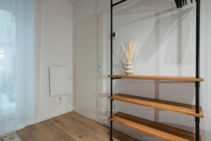 A room with a wooden floor, a white door, a wall-mounted shelf with a vase, and a power outlet. - 2-room apartment with a terrace and queen-size bed (Wien)