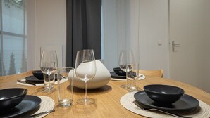 Ein Esstisch mit klarem Glas, schwarzen Tellern und einer weißen Kanne.