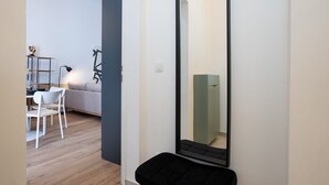 Ein modernes Interieur mit einem großen Spiegel, einer schwarzen Bank, einem weißen Stuhl und einem grauen Sofa.