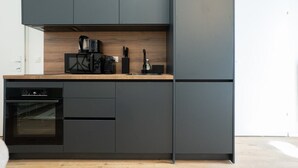 Eine moderne Küche mit dunklen Schränken, einer Holz Arbeitsplatte und einem eingebauten Backofen.
