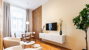 Een moderne woonkamer met een televisie, bank, eettafel en stoelen.