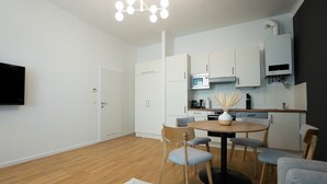 Una cocina moderna con armarios blancos, un microondas y una estufa. Hay un comedor con una mesa redonda y cuatro sillas.