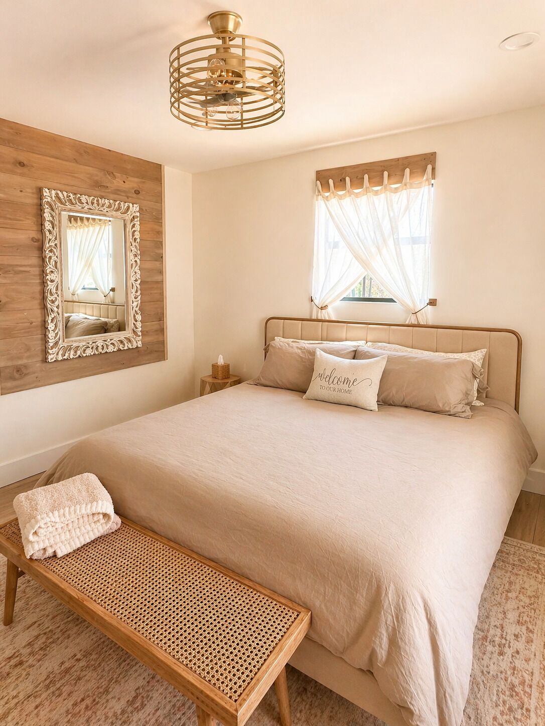 A bedroom with a bed, a bench, a mirror, a ceiling fan, and a window with curtains.