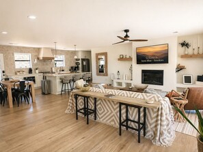 A modern living room with a fireplace, a dining area, and a kitchen with a stone accent wall. - Single Level Luxe Mtn Home w/Arcade, Hot Tub, Fire Pit and Grill (Gatlinburg)
