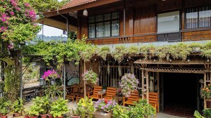 A wooden house with a covered porch, potted plants, and outdoor seating. - Home Stay Mai Châu Moment (Mai Ha)