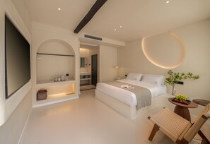A modern bedroom with a large bed, bedside tables, a TV, and a small dining area with a table and chairs. - Yijianju Garden Inn (Lijiang)