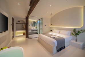 A modern bedroom with a large bed, a walk-in closet, a bathroom with a bathtub, and a large mirror. - Yijianju Garden Inn (Lijiang)