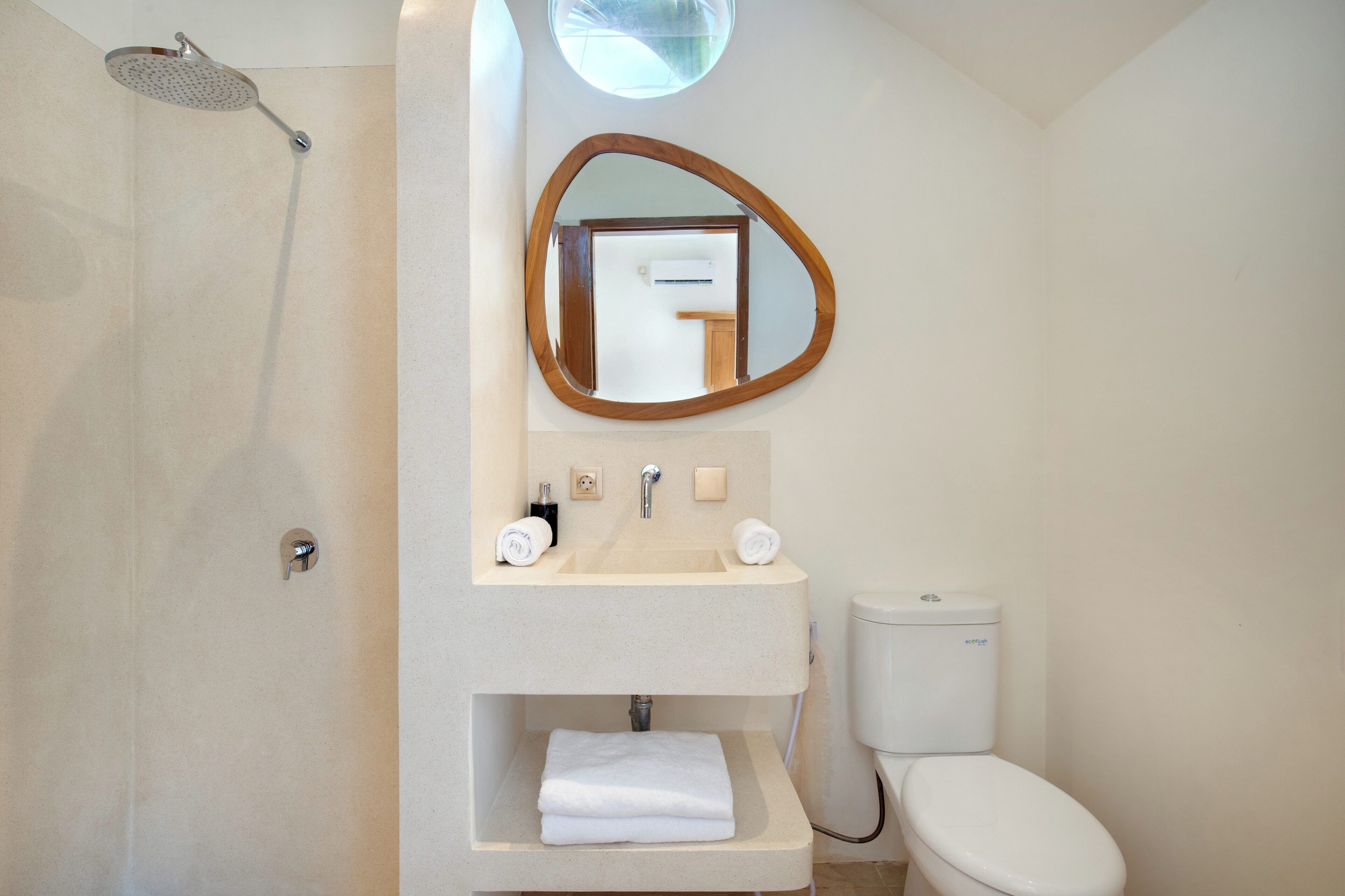 Un baño con ducha, lavamanos, espejo e inodoro.