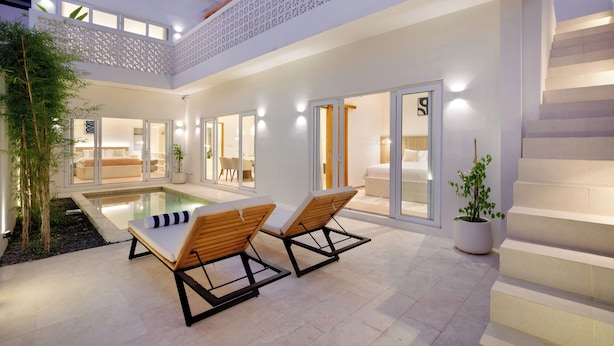 Ein modernes Haus mit Swimmingpool, zwei Liegestühlen und einer Treppe.