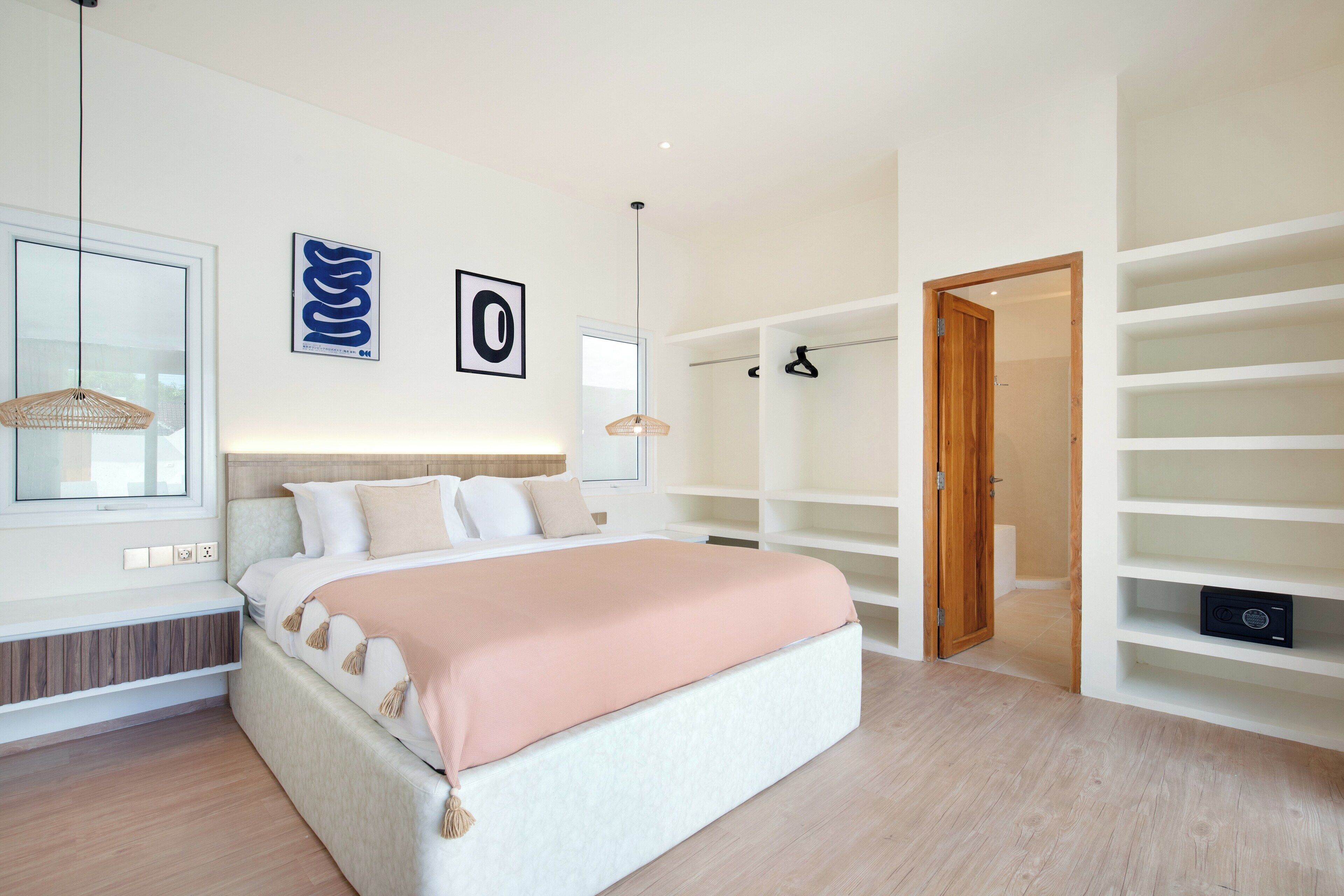 Et moderne soveværelse med en stor seng, indbyggede reoler og et walk-in closet.