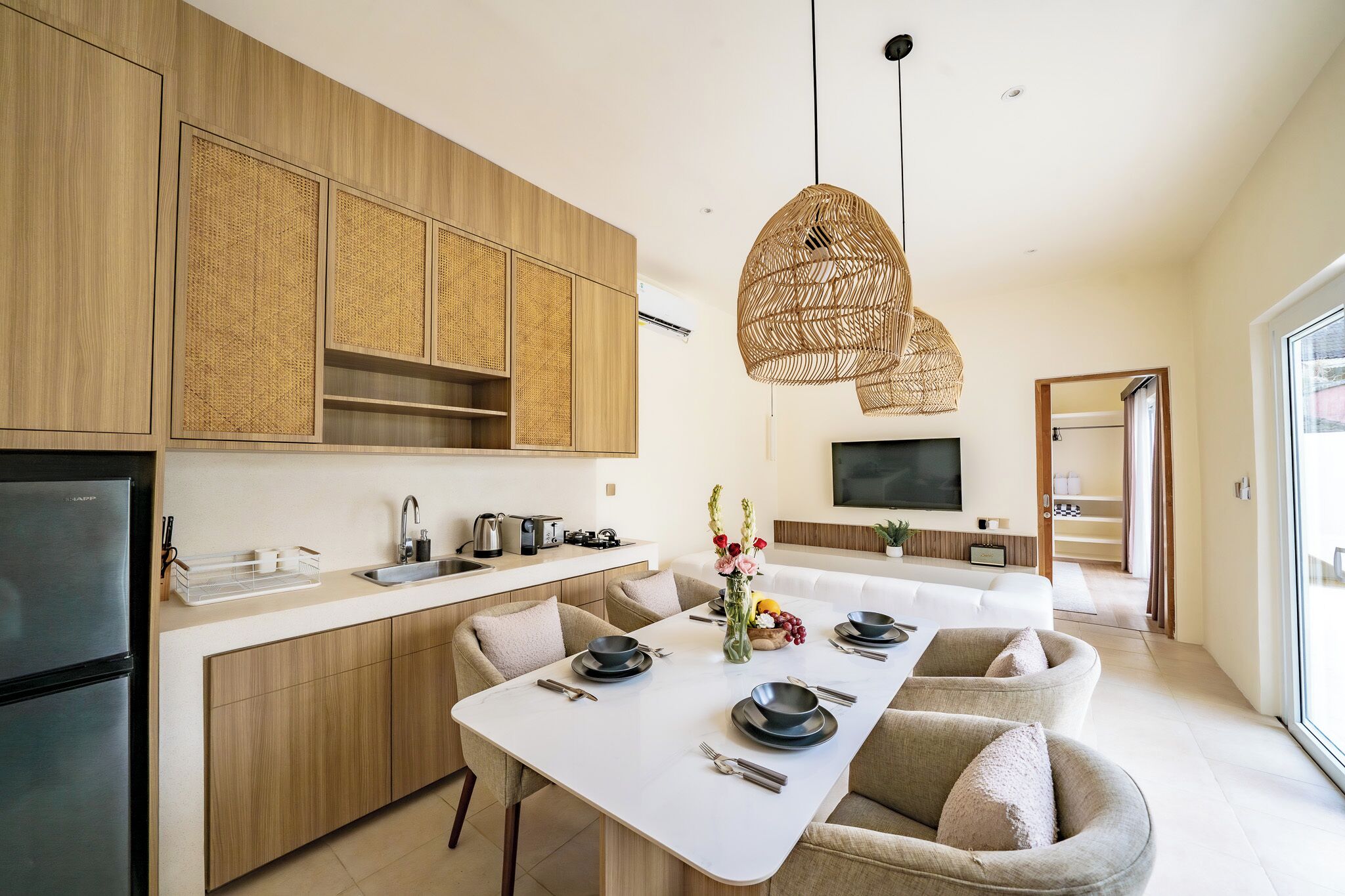 Una cucina moderna con mobili in legno, un tavolo da pranzo bianco e una lampada a sospensione.