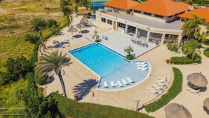 Ett semesterhotell med en swimmingpool, solstolar och en byggnad med ett rött tak.